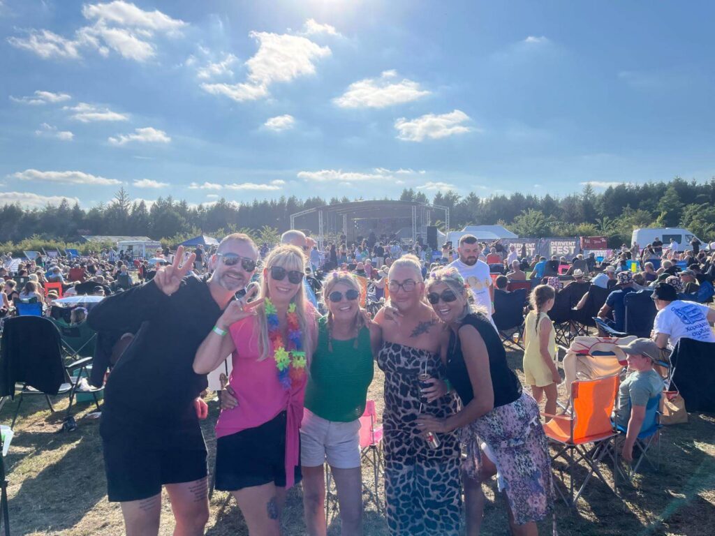 A group of adults in bright clothing enjoying themselves at the main stage at Derwent Fest