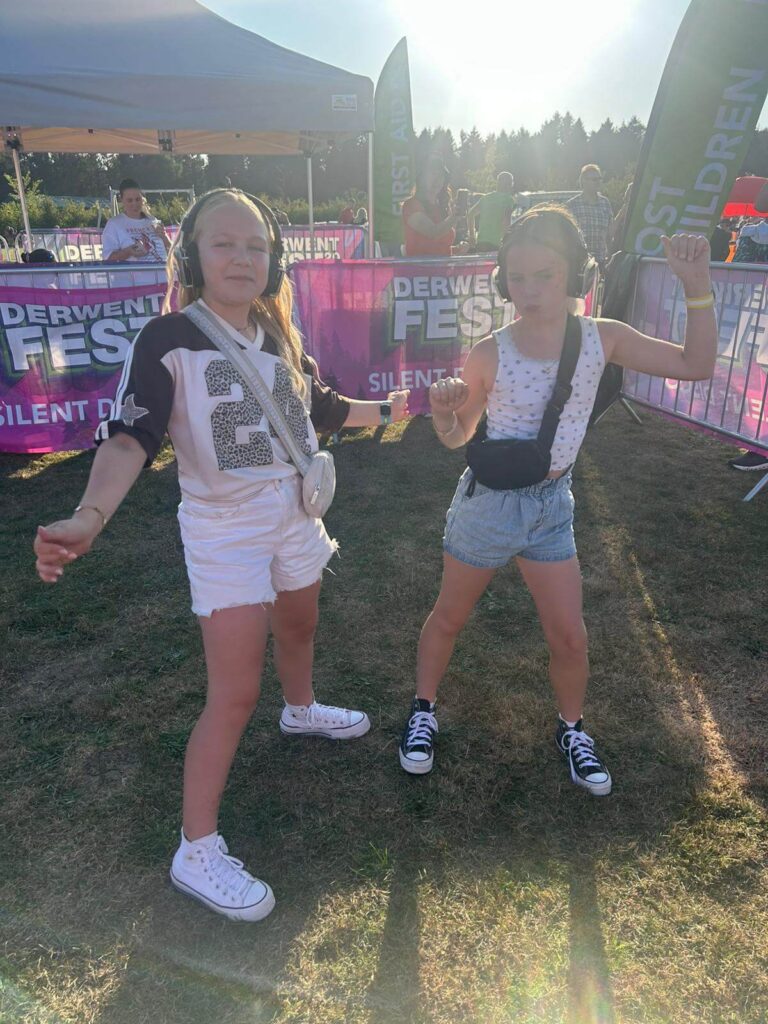 Two young girls dancing with headphones on at a silent disco