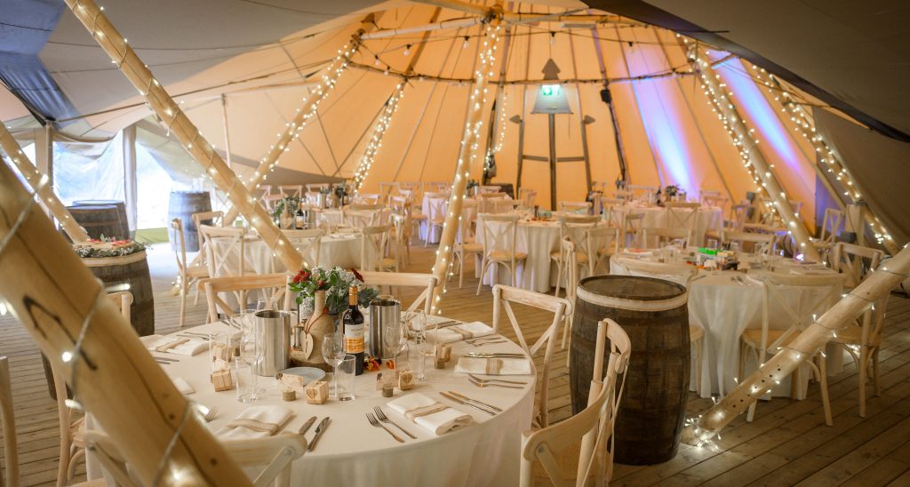 Inside of the Teepee at Kielder Waterside Park. The tables are decorated with white and dinner settings for a wedding