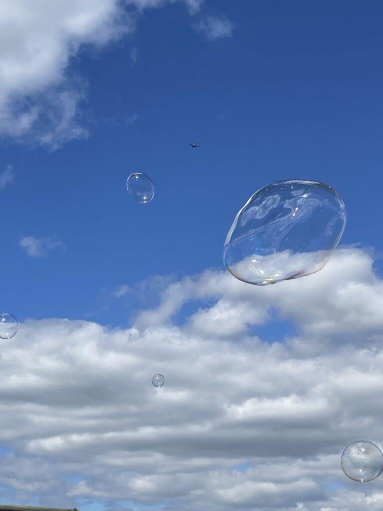 Bubble floating against a blue sky with some clouds